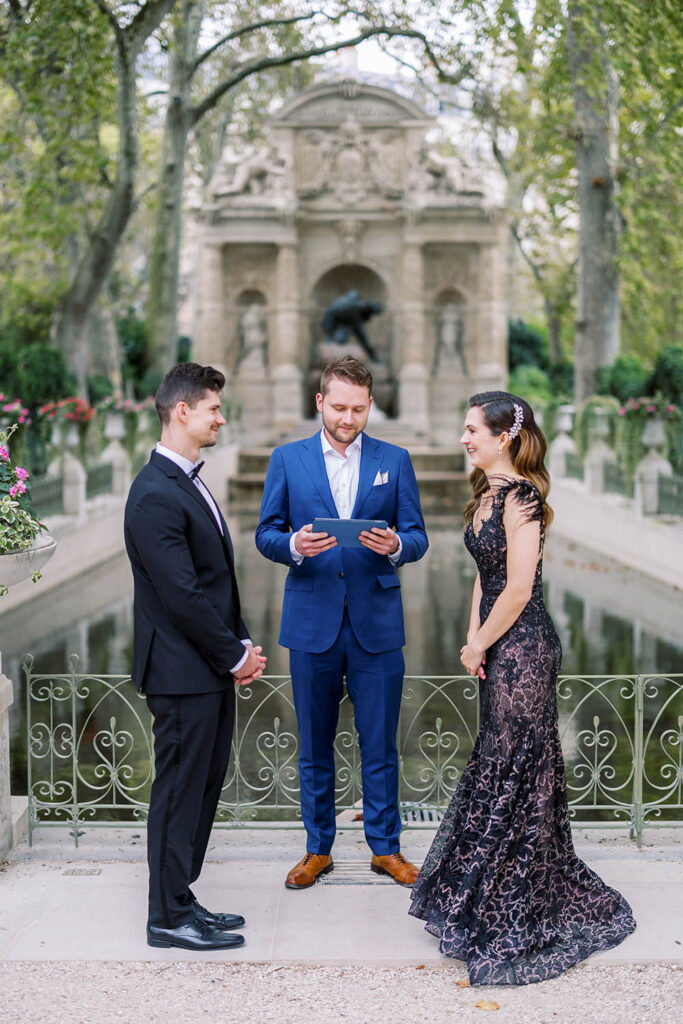 a couple exchanging vows in front of the Medici Fountain in Luxembourg Gardens in Paris