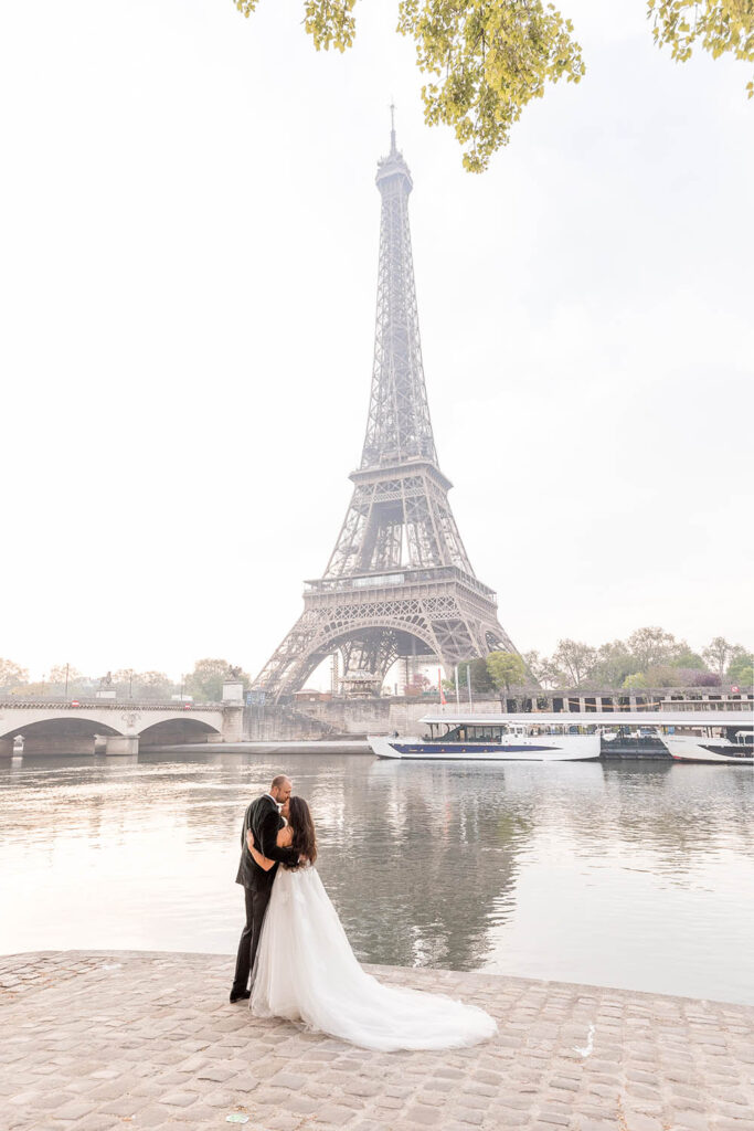 a couple kissing along the banks of the Seine in Paris in front of the Eiffel Tower