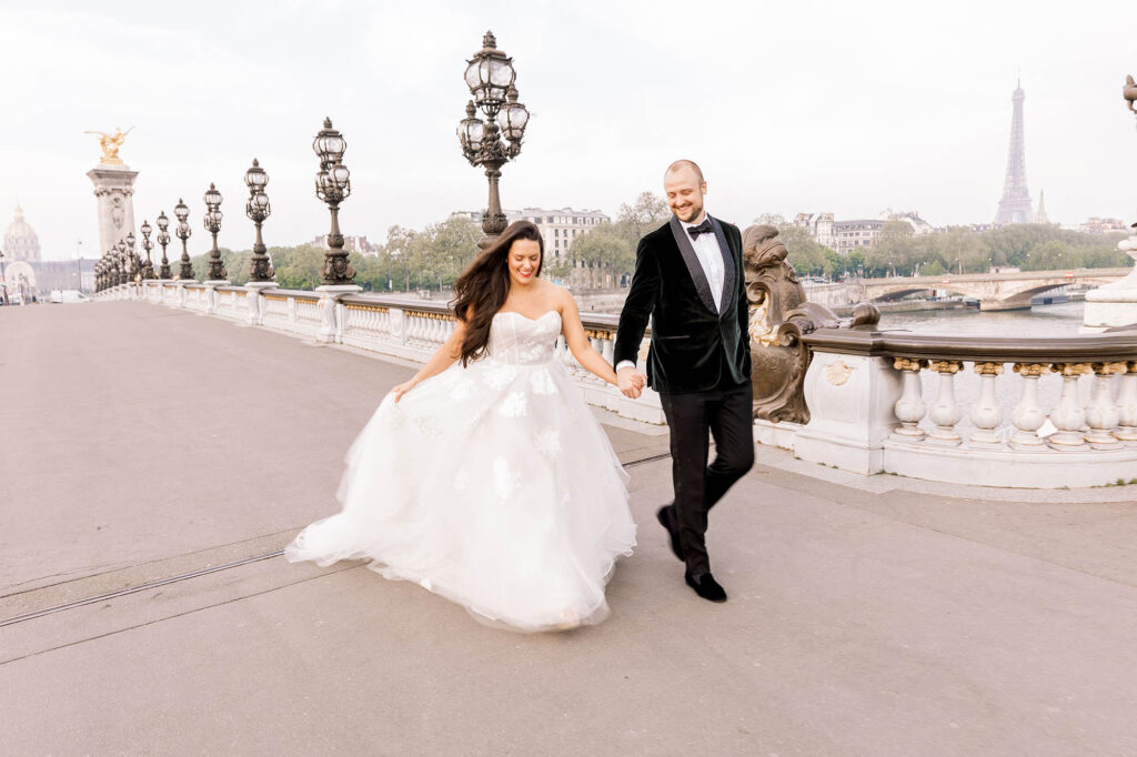 bride and groom walking and holding hands on Pont Alexandre III in Paris